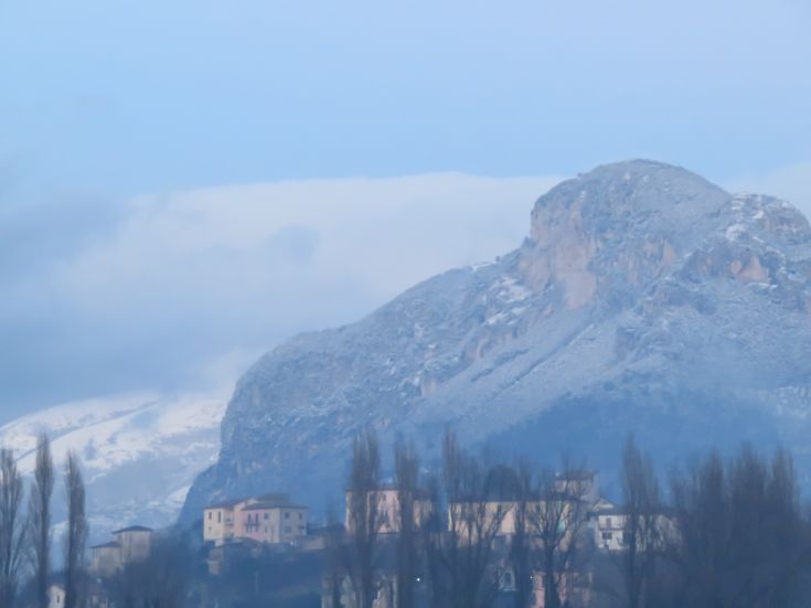A snow-covered mountain towering over a peaceful Umbrian village.