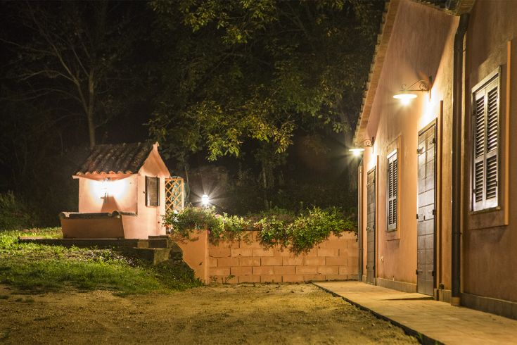 A nighttime scene of a hospitality building, illuminated with greenery around.