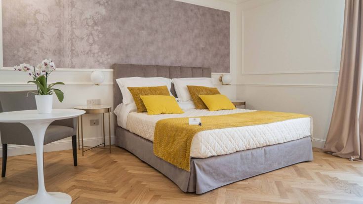 Camera accogliente e tranquilla dotata di letto matrimoniale e tonalità gialle sulle pareti.