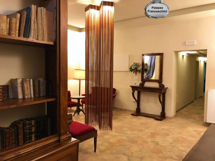 Interno di un salotto con libreria e lampada, situato all'interno di un palazzo storico.