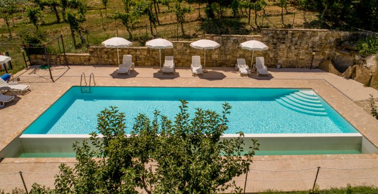 Un accogliente agriturismo con piscina esterna, circondato dal verde tipico dell'Umbria.