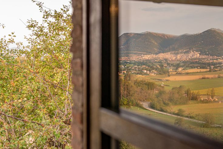 Scena di un agriturismo immerso nella campagna, circondato da montagne e vegetazione.