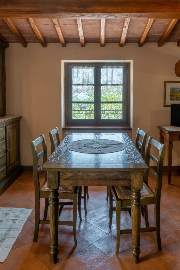 Una sala da pranzo accogliente con tavolo in legno e sedie, illuminata dalla finestra che si affaccia su un panorama verde.