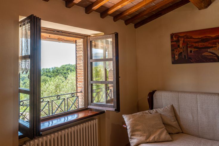 Scena di un appartamento con una finestra che si affaccia su un paesaggio naturale e rustico.