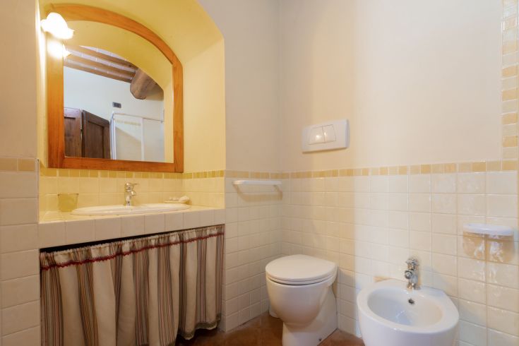 Bagno semplice con pavimento in ceramica e illuminazione morbida.