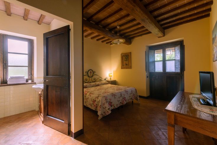 Camera in un agriturismo, con arredi semplici e un'ottima illuminazione naturale.