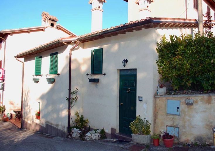 Street-side exterior entrance of the one-story building with a green door and green shutters