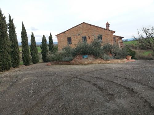 A 17th-century farmhouse nestled in the countryside, surrounded by cypress trees and olive groves.