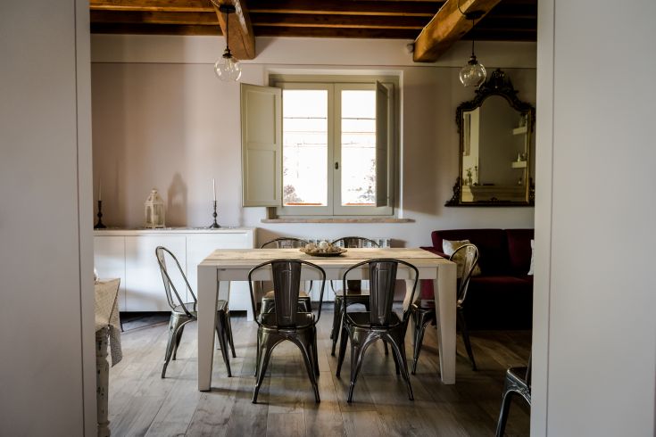 Spaziosa sala da pranzo dotata di tavolo in legno e sedie metalliche, illuminata da ampie finestre.