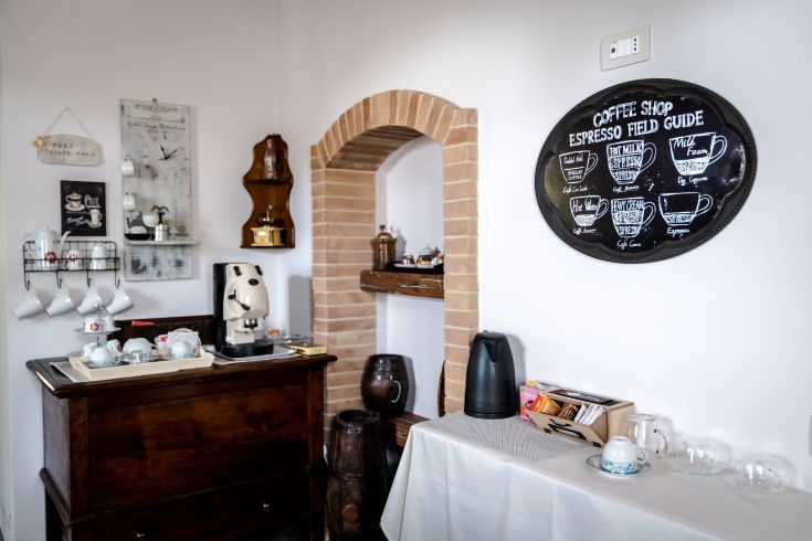 Un angolo di un caffè con attrezzature per la preparazione di bevande calde e semplici decorazioni.