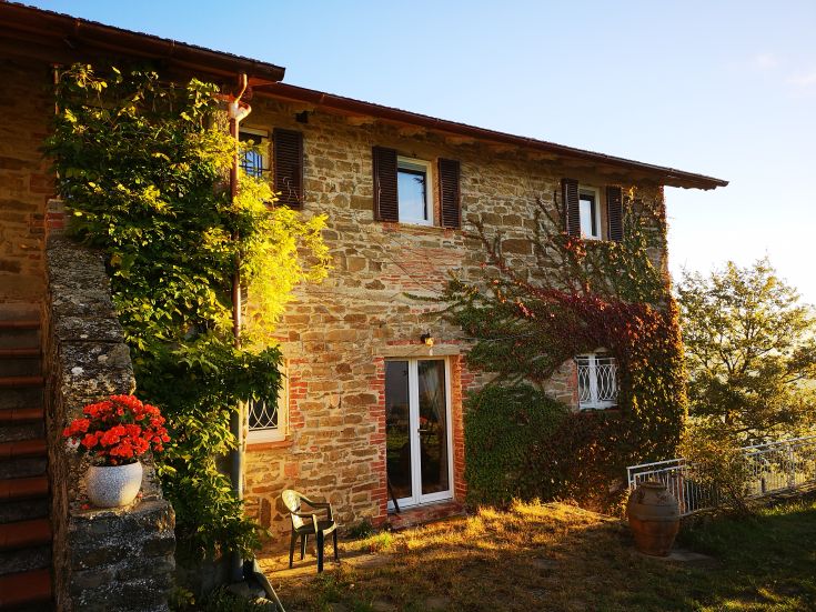 A stone building surrounded by greenery, trees, and flowers, perfect for peaceful moments in nature.