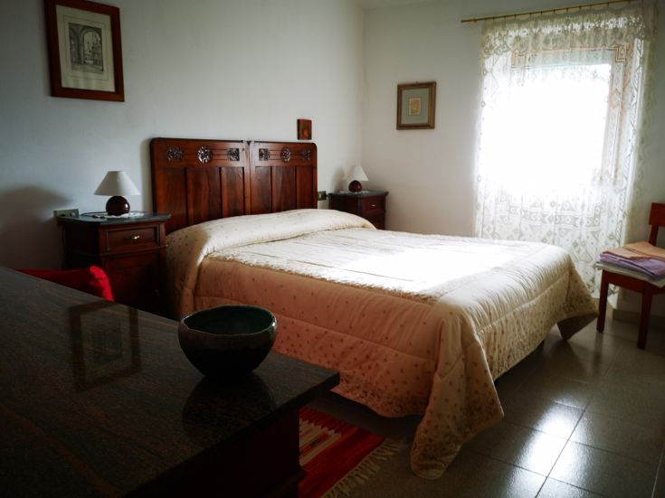 Simple bedroom with a double bed and wooden furniture, perfect for a relaxing stay.