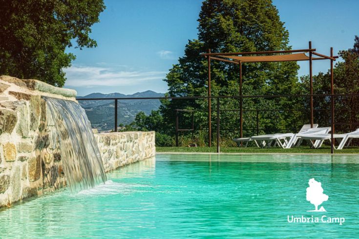 A pool surrounded by trees, providing a view of the gentle Umbrian hills.