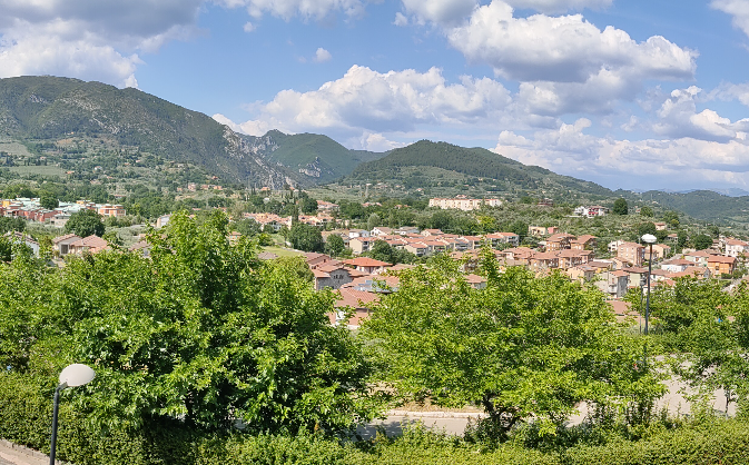 A charming village scene surrounded by green hills and soft clouds in the sky.