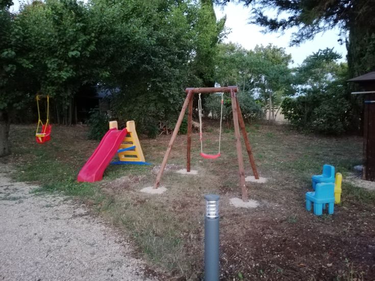 Un parco giochi tranquillo per bambini, dotato di altalene, scivoli e panchine, immerso nel verde.