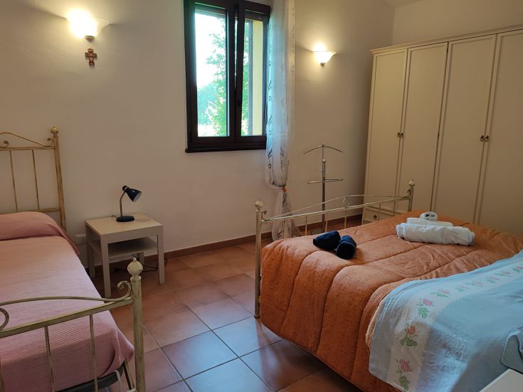 Camera confortevole e luminosa con un letto matrimoniale e arredamento essenziale.