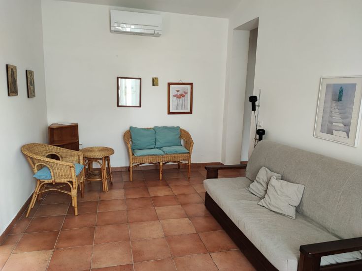 Soggiorno confortevole con TV e finestre che si affacciano su un ampio spazio verde per un'atmosfera tranquilla.