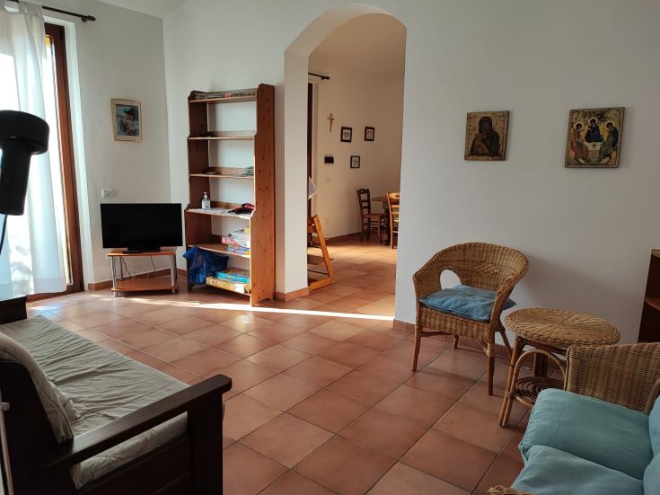 Soggiorno confortevole con TV e finestre che si affacciano su un ampio spazio verde per un'atmosfera tranquilla.