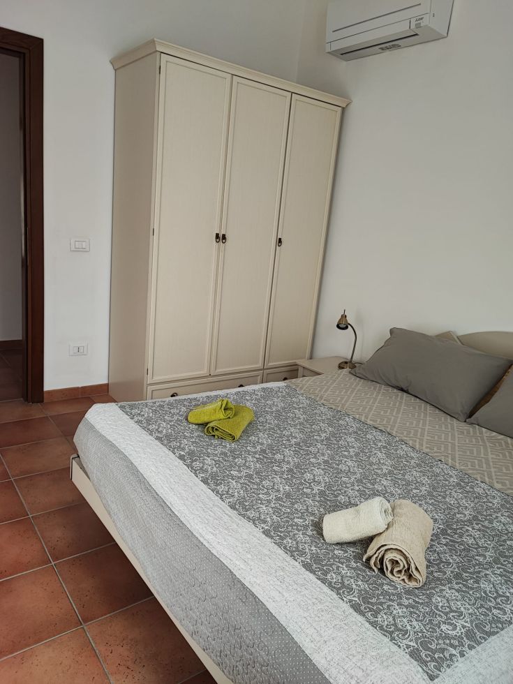 Camera confortevole e luminosa con un letto matrimoniale e arredamento essenziale.