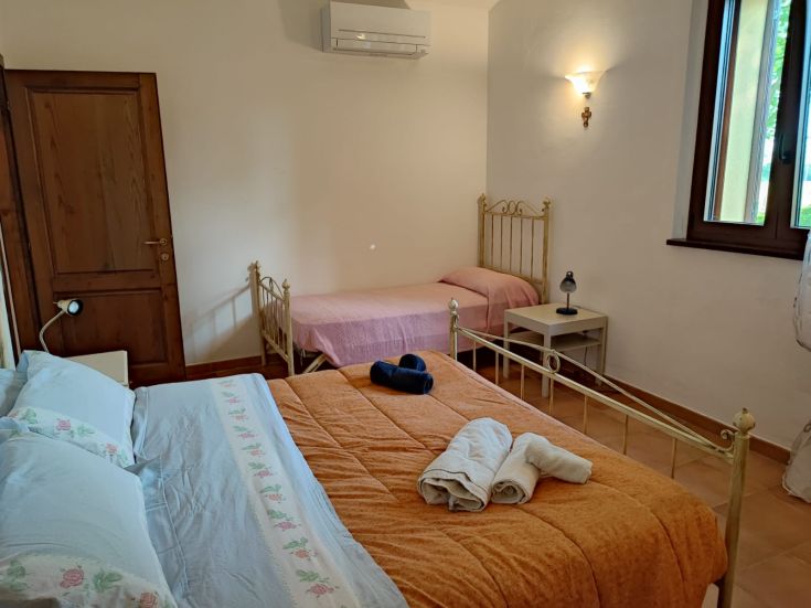 Camera confortevole e luminosa con un letto matrimoniale e arredamento essenziale.