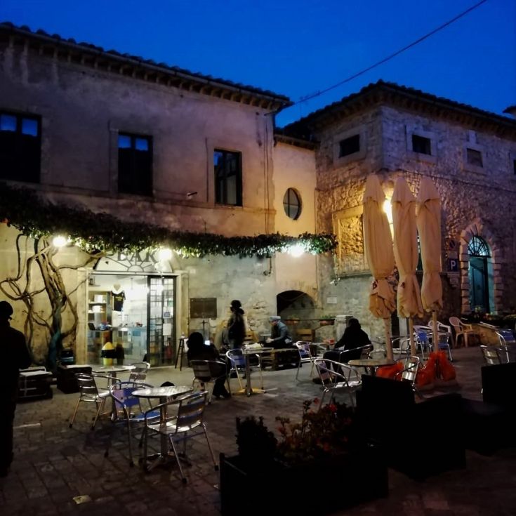 Une soirée calme dans un village historique, avec des tables extérieures et une ambiance agréable.