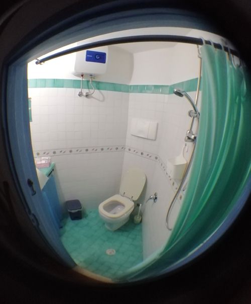 Salle de bain fonctionnelle et sobre avec douche et sanitaires essentiels.