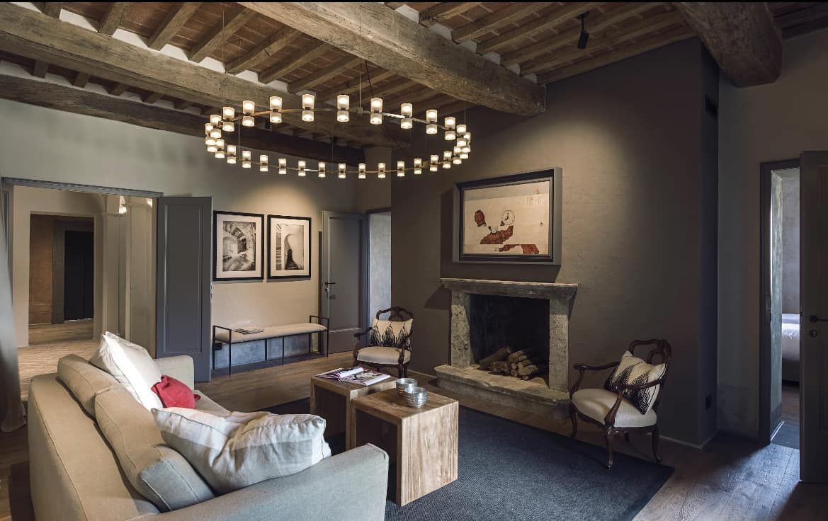 Un soggiorno con soffitti a travi in legno e un grande lampadario moderno. Spazio accogliente e ben arredato.