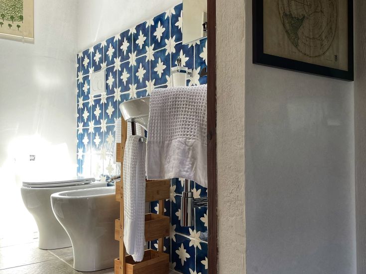 Ein Badezimmer mit blauen Fliesen und weißen Handtüchern, das eine komfortable Atmosphäre ausstrahlt.