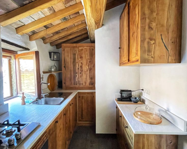 Holzküche mit Balkendecke und großen Fenstern, die natürliches Licht in den Raum bringen.