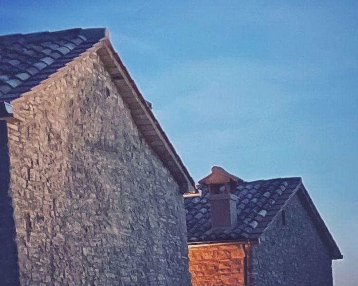Zwei Steingebäude unter einem blauen Himmel, die den typischen architektonischen Stil der Valtiberina darstellen.