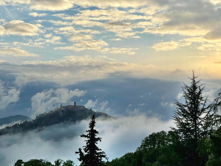 Ein Gebäude ragt in den Himmel über einer ruhigen umbrischen Landschaft.