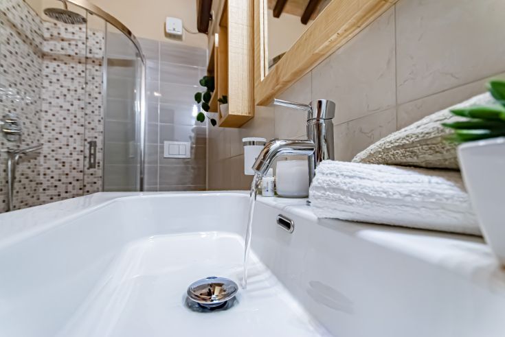 A modern bathroom featuring a shiny sink and faucet, with towels neatly arranged.