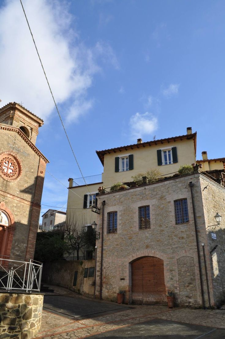 A picturesque corner of an Umbrian village with stone buildings under a clear sky.