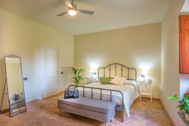 Accogliente camera con letto matrimoniale, caratterizzata da un'atmosfera rustica e luminosa.