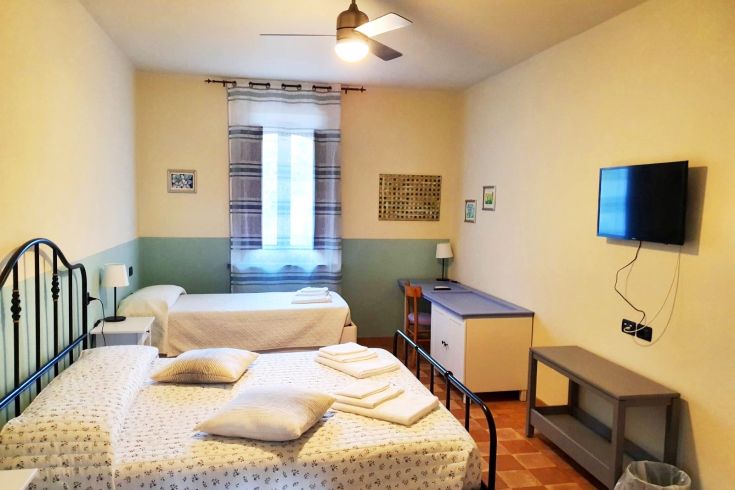 Camera in un palazzo medievale, arredata con letti semplici e dotata di TV, per un soggiorno tranquillo.