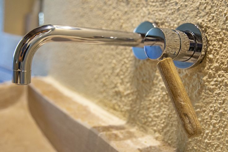A close-up of a modern faucet with a sleek design and wooden handle, ideal for contemporary and natural settings.