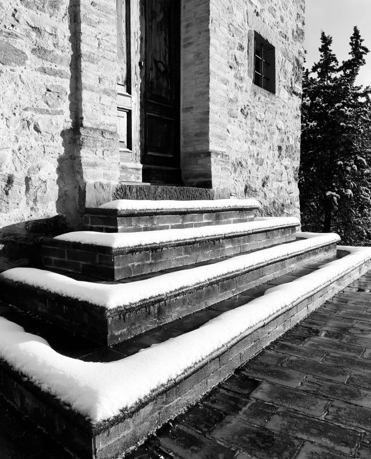 White stairs leading to a simple entrance, surrounded by lush greenery.