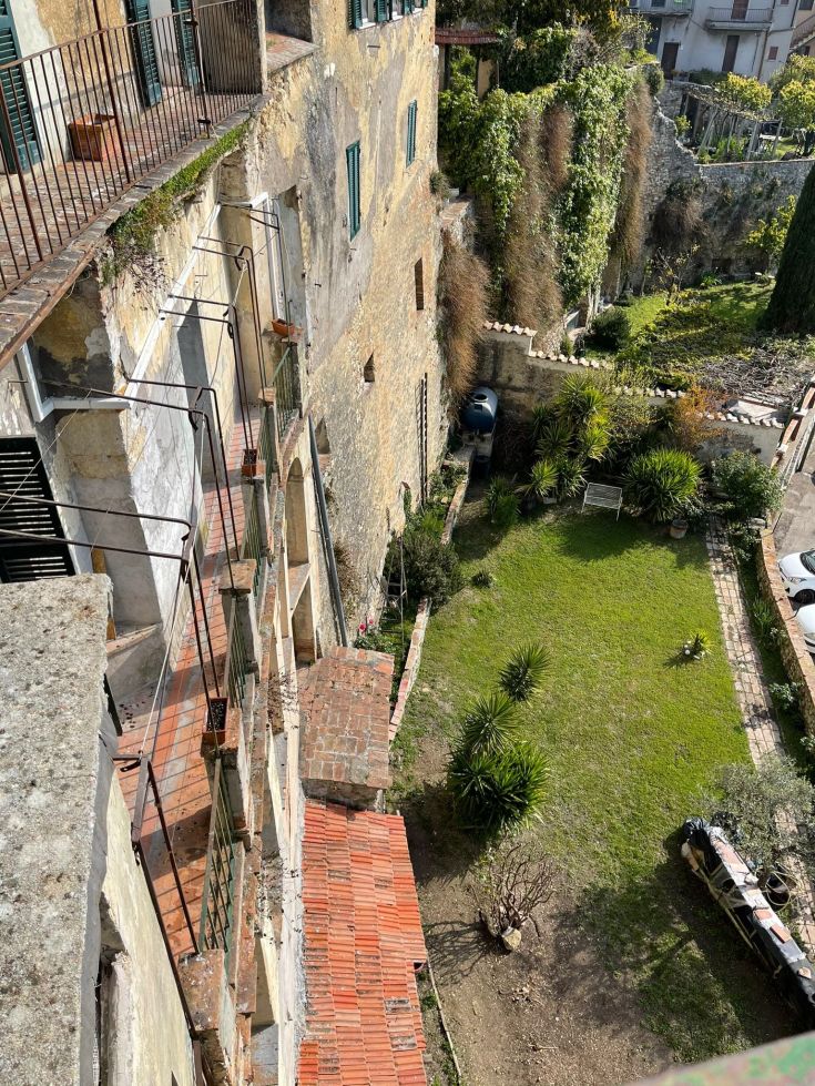 Scena di un giardino all'interno di un palazzo, con terrazze e una varietà di piante.