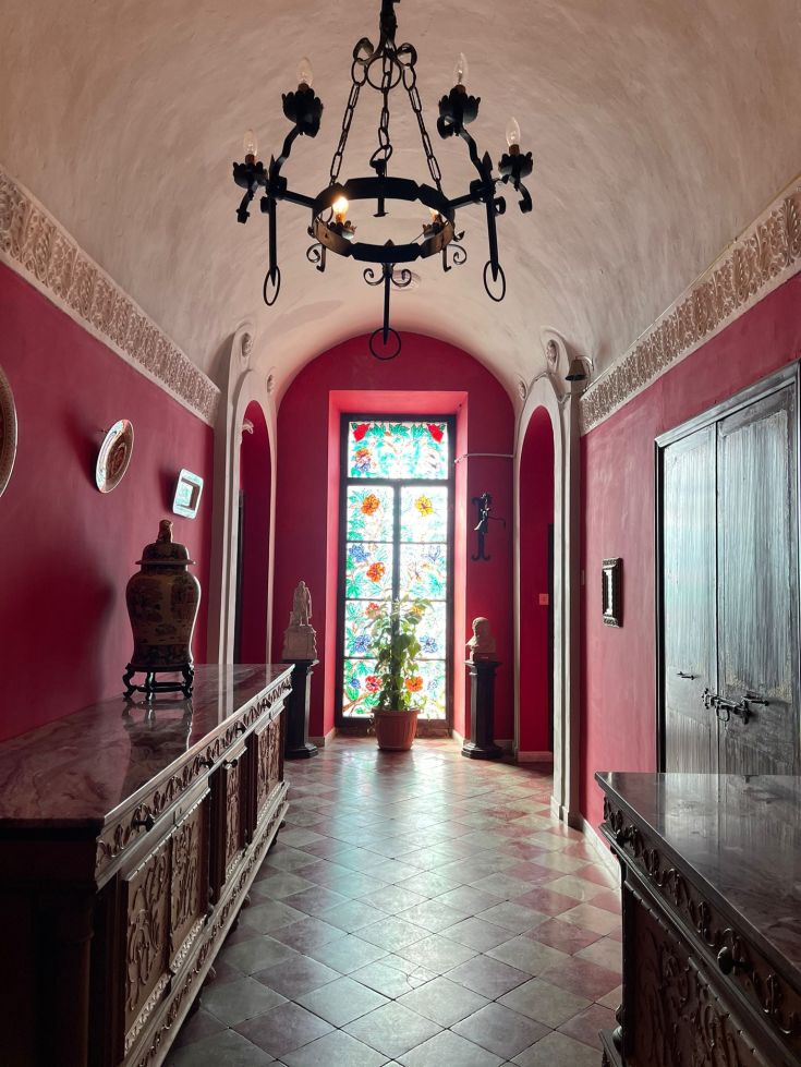 Interno di un palazzo con pareti rosse e finestre colorate, dando una sensazione accogliente.