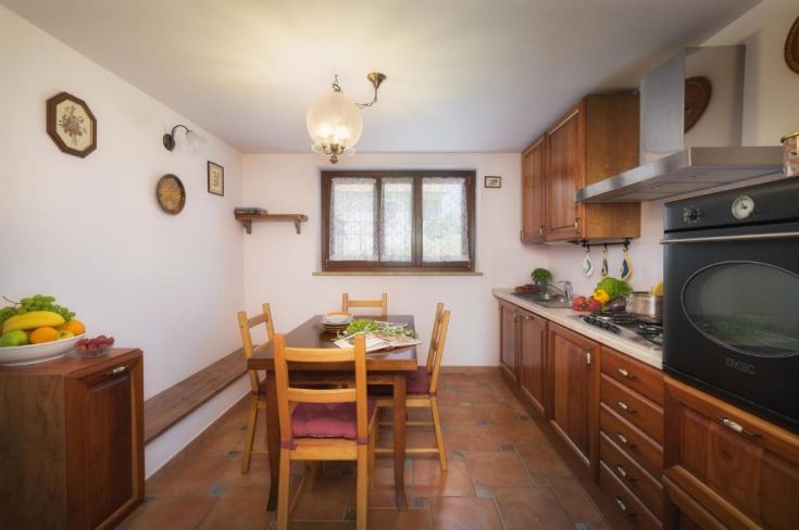 Gemütliche Küche mit Holzmöbeln, perfekt für gesellige Abendessen an einem großen Tisch.