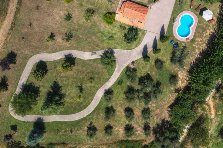 Ein Landhaus in einer grünen Umgebung mit einem Pool, Garten und Joggingpfaden.