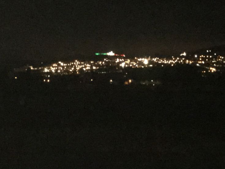 Una scena notturna caratterizzata dalle luci di un centro urbano che illuminano l’orizzonte.