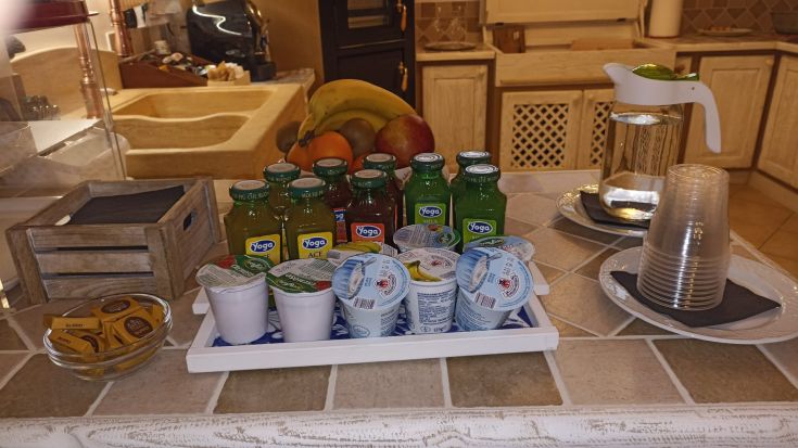 Una varietà di bevande e yogurt su un tavolo, con della frutta in primo piano.