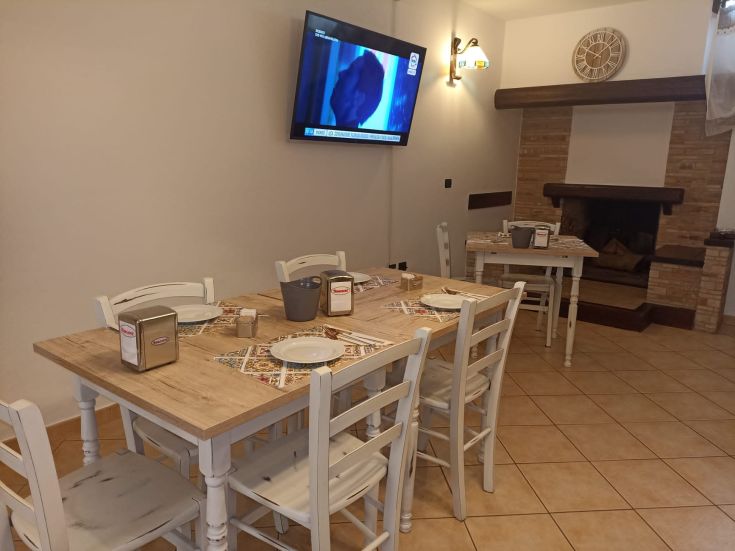 Interni di un ristorante con tavoli di legno e un camino, adatti per cene rilassate.