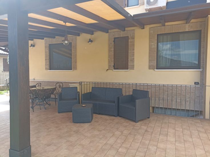 Spazio esterno di un B&B con arredi semplici e un tavolo per rilassarsi, circondato da verde.