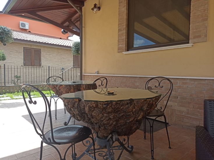 Un'area esterna semplice con tavoli in legno e sedie in metallo, adatta per momenti di relax.