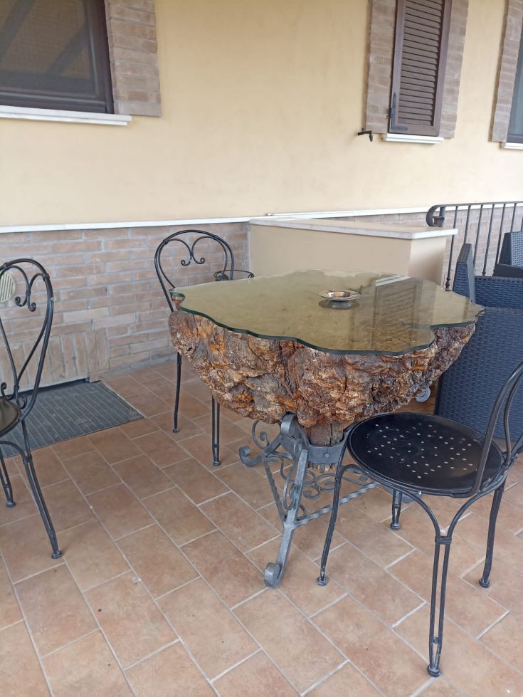 Tavolo in legno con piano in vetro, situato nella veranda di un'accogliente struttura in Umbria.