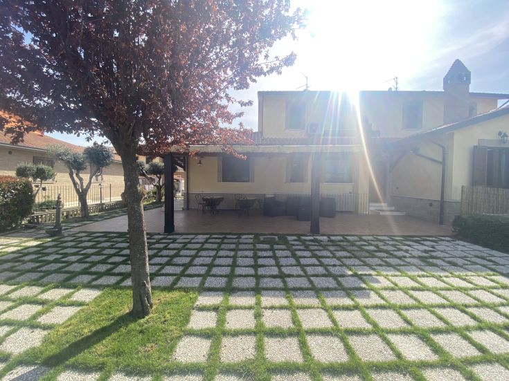 Esterno di un edificio con giardino curato e un albero visibile in primo piano.