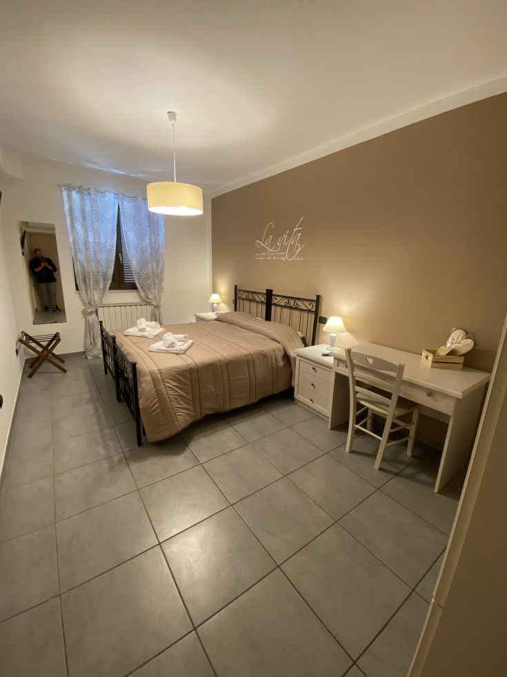 Camera confortevole con letti, scrivania e illuminazione soffusa. Arredamento funzionale e design sobrio.