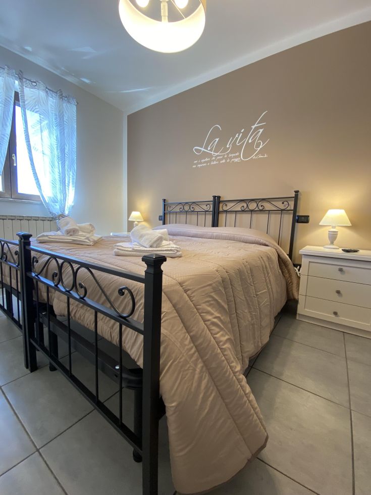 Camera matrimoniale spaziosa e luminosa con arredi semplici e decorazioni sobrie.